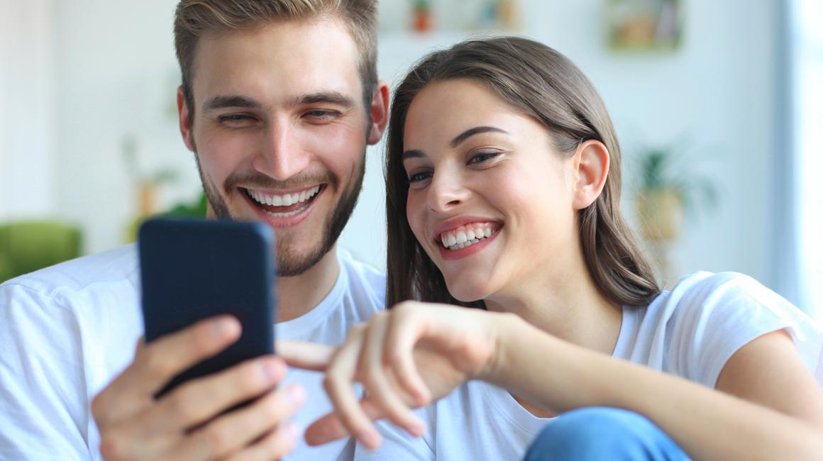młoda para patrzy na komórkę, którą trzyma chłopak