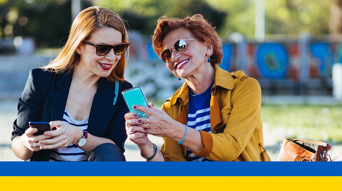 dwie panie w średnim wieku z komórkami, coś sobie tłumaczą ukr