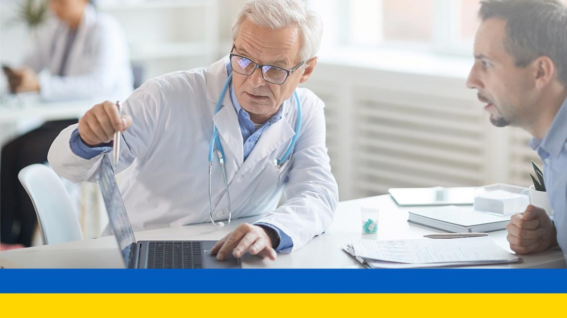 Lekarz pokazuje coś pacjentowi w komputerze ukr