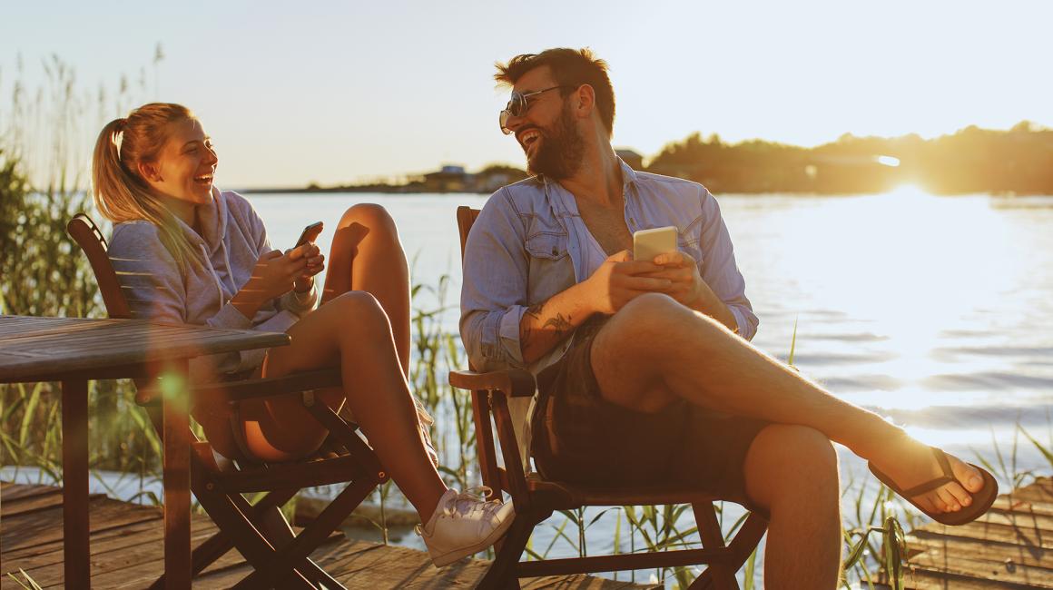 para na leżakach nad jeziorem z komorkami i uśmiechami