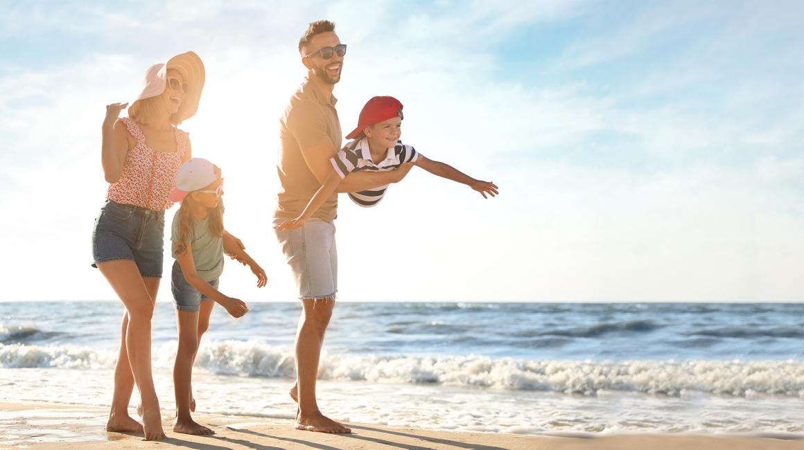 rodzina na plazy, rodzice, dwoje dzieci, chłopca ojciec trzyma na rękach w pozycji samolotu