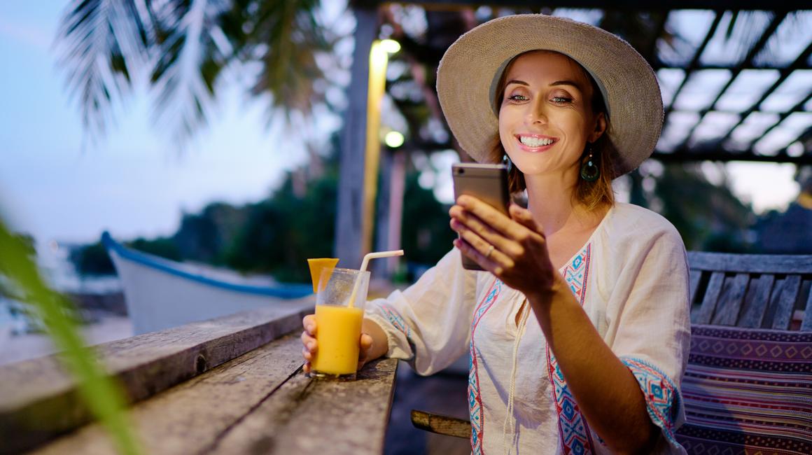Kobieta w słomianym kapeluszu z sokiem ponarańczowym w tle palmy