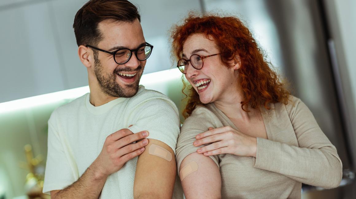 Mężczyzna i kobieta pokazują, że są zaszczepieni, uśmiechy