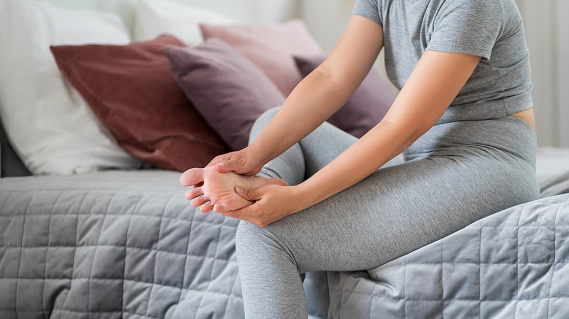 kobieta siedzi na tapczanie i masuje sobie stopę