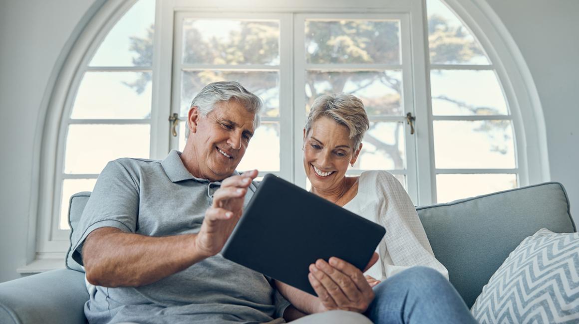 Mężczyzna i kobieta w średnim wieku patrzą w tablet, który trzyma mężczyzna