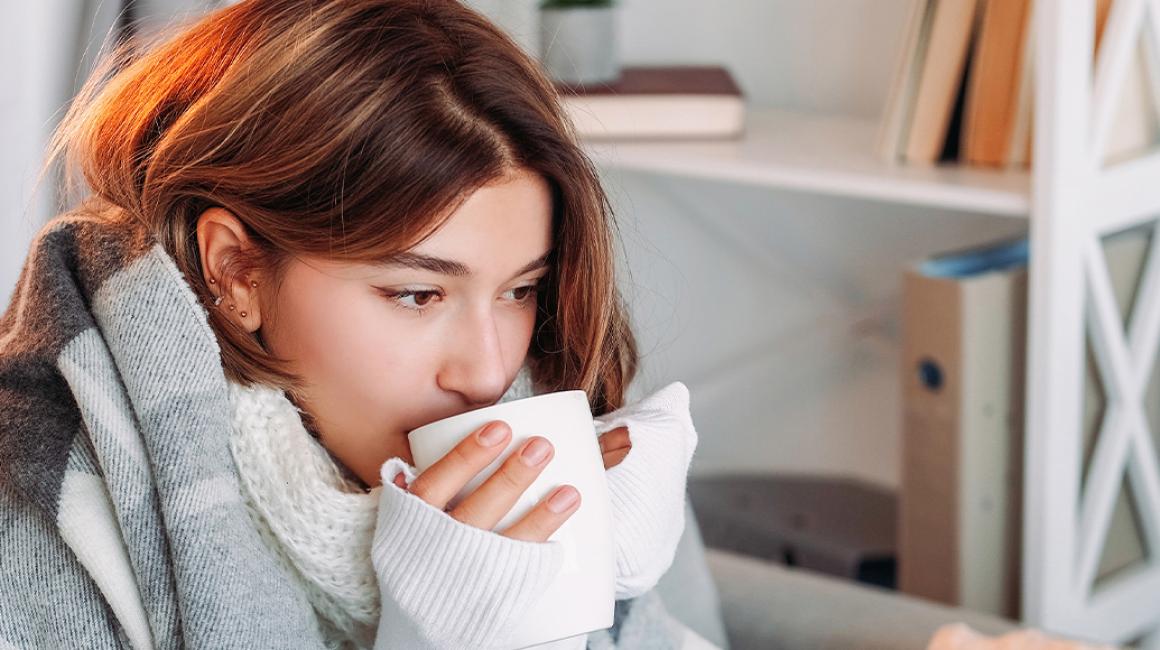 Dziewczyna pod kocem z kubkiem