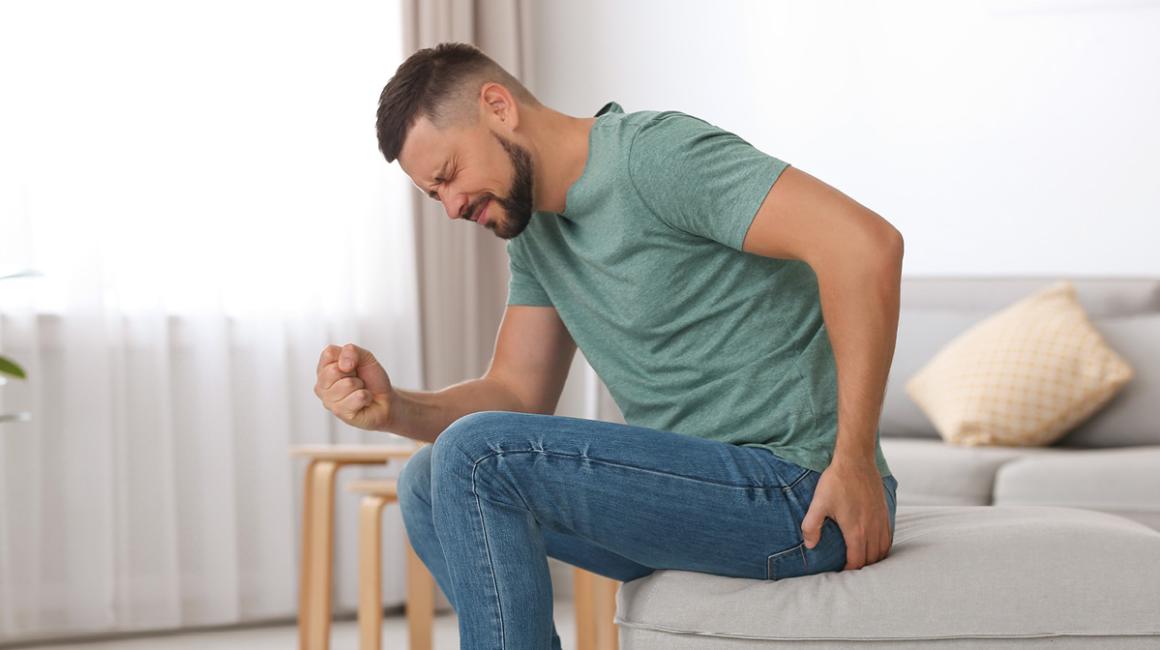 mężczyzna podnosi się chwytając się za pośladek