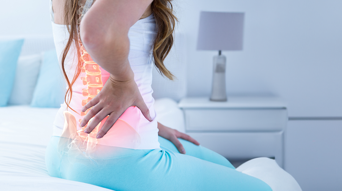 Kobieta trzyma rękę na bolącym kręgosłupie
