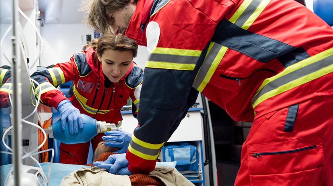 dwoje ratownikow w karetce robi masaż serca