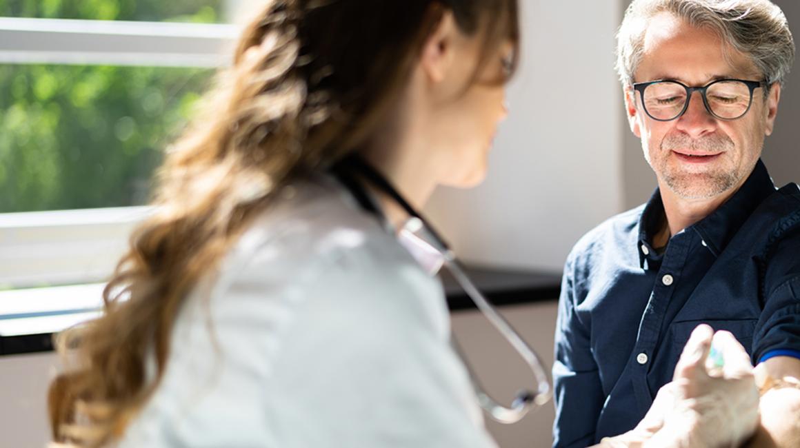 Lekarka pobiera krew starszemu mężczyźnie w okularach.