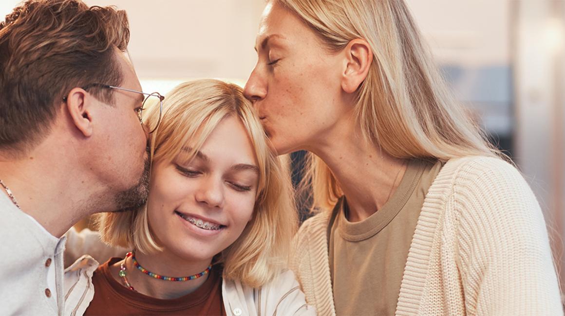 Rodzice obejmują i całują nastolatkę