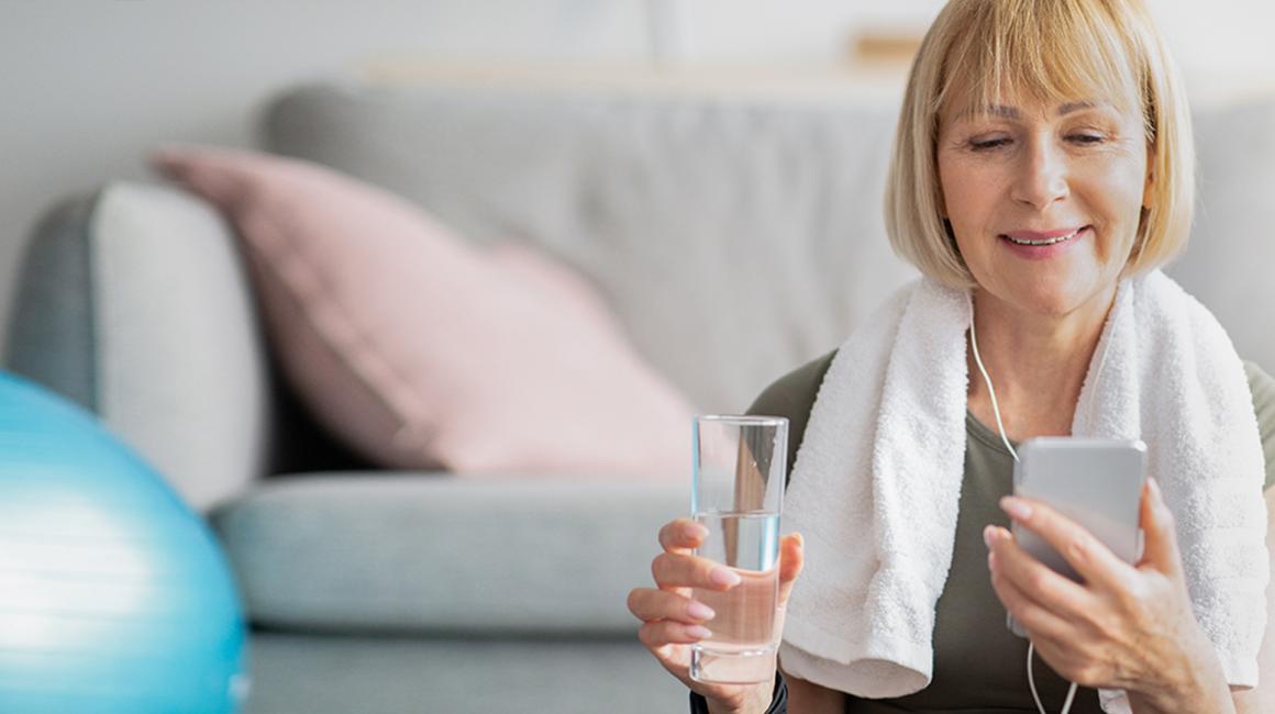 Kobieta po ćwiczeniach patrzy na telefon