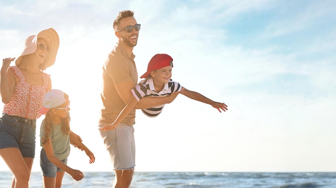 rodzina na plazy, rodzice, dwoje dzieci, chłopca ojciec trzyma na rękach w pozycji samolotu