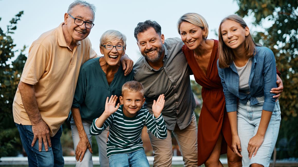 Uśmiechnięta rodzina pozuje do zdjęcia - dziadek i babcia, tata i mama, syn i córka.