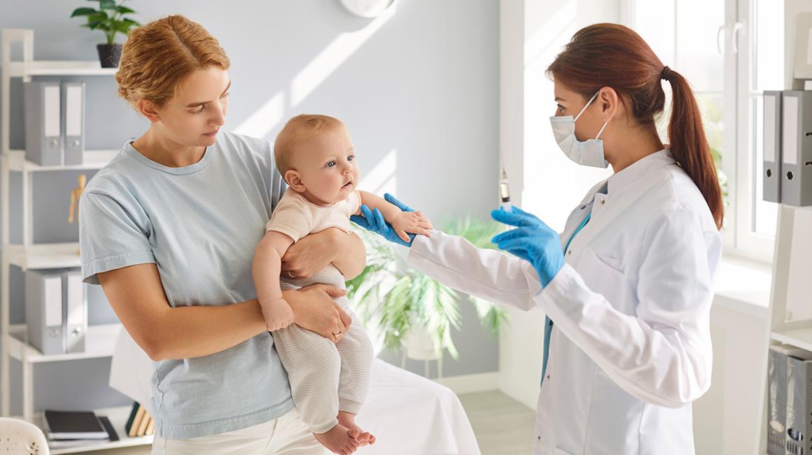 kobieta z małym dzieckiem, lekarka trzyma strzykawkę