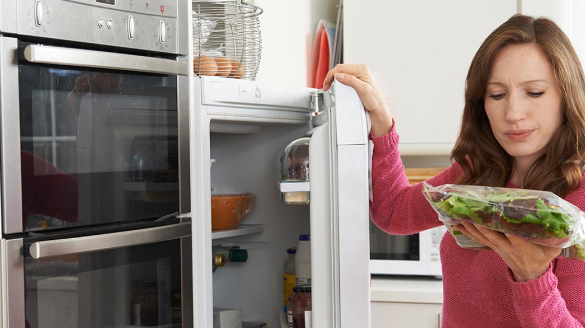 Kobieta ogląda jedzenie wyjęte z lodówki