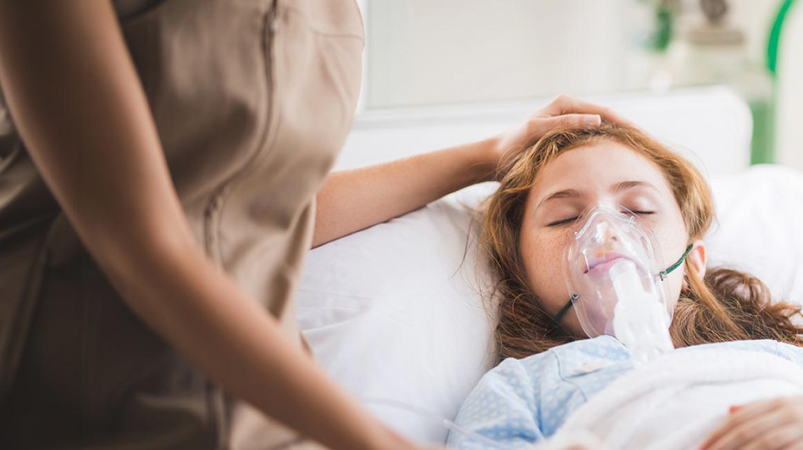 Dziewczynka leży w łóżku w masce tlenowej