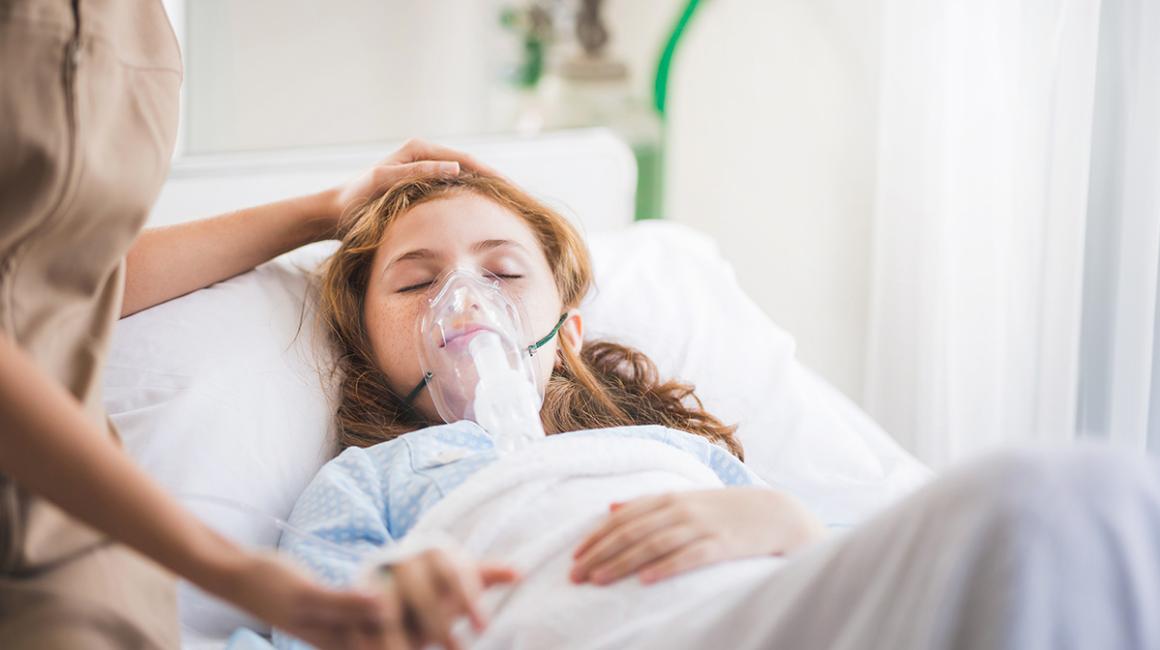 dziewczynka leży w łóżku w masce tlenowej