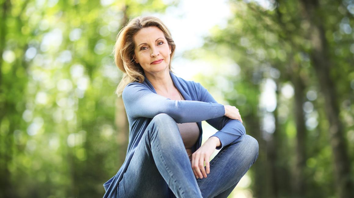 Kobieta siedzi na trawie w lesie