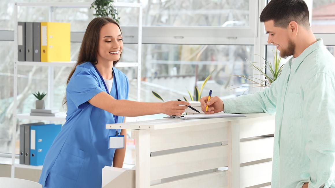 Rejestratorka pokazuje pacjentowi formularz