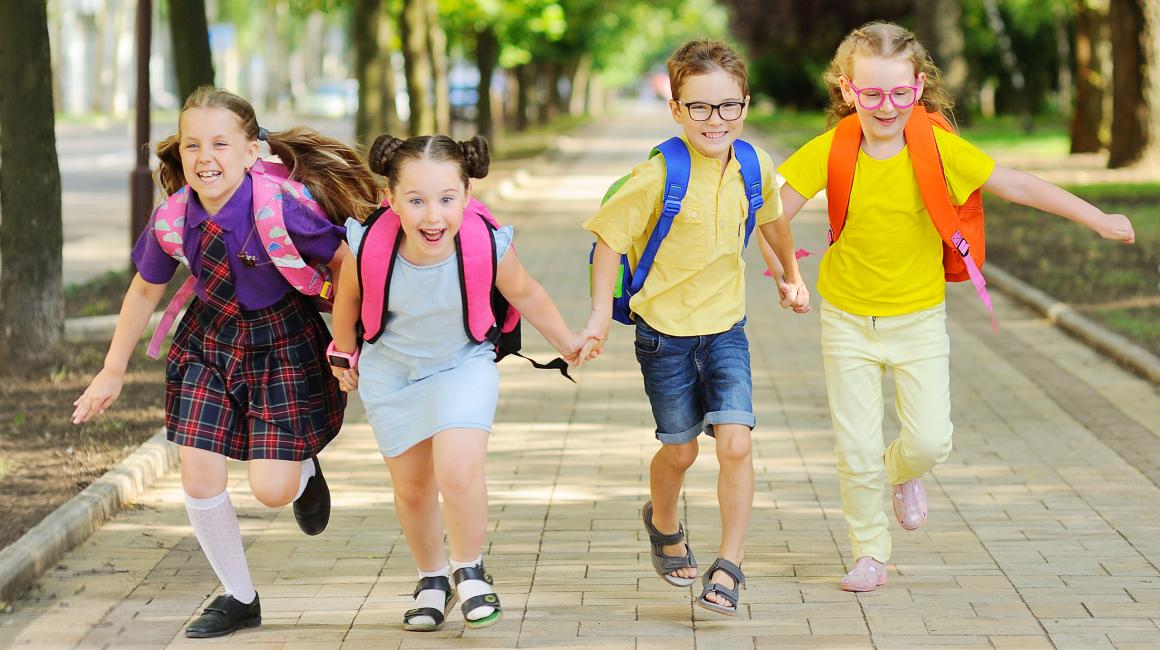 Czwórka dzieci ok. 10 lat z tornistrami, biegnie razem 