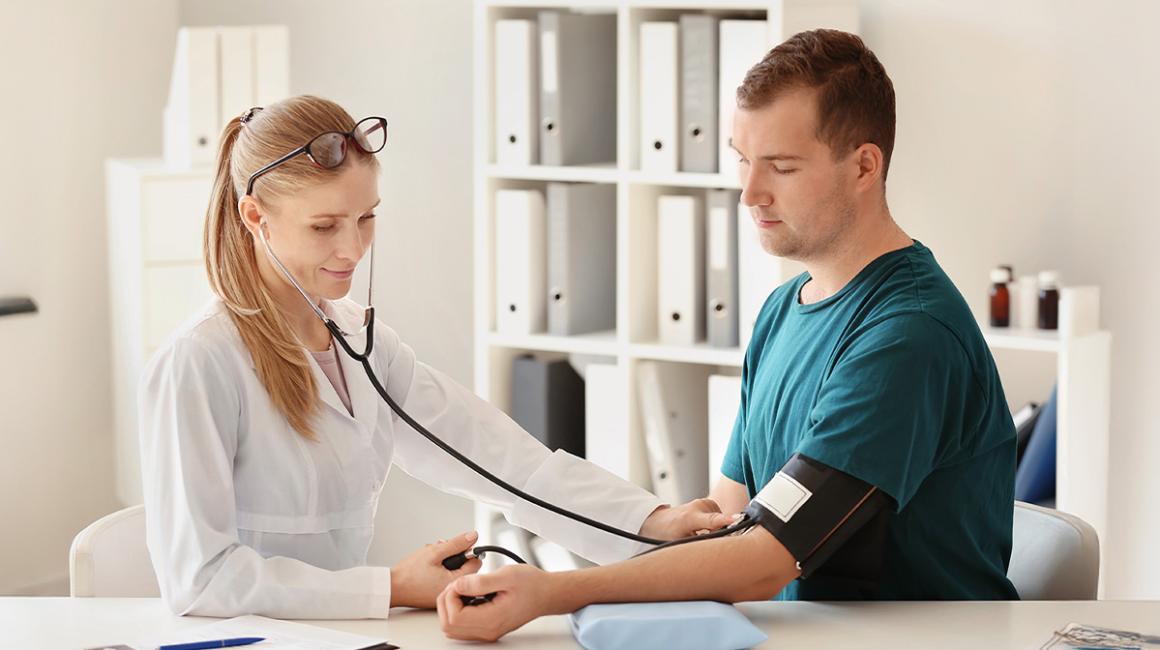Lekarka mierzy ciśnienie krwi młodemu mężczyźnie