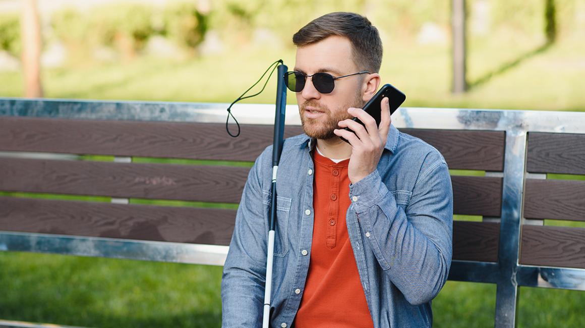 niewidomy mężczyzna z telefonem na ławce