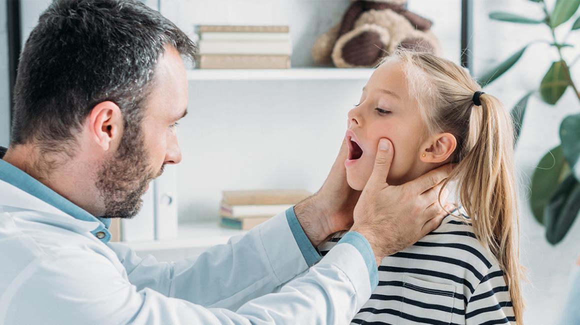 Lekarz zagląda do gardla dziewczynki