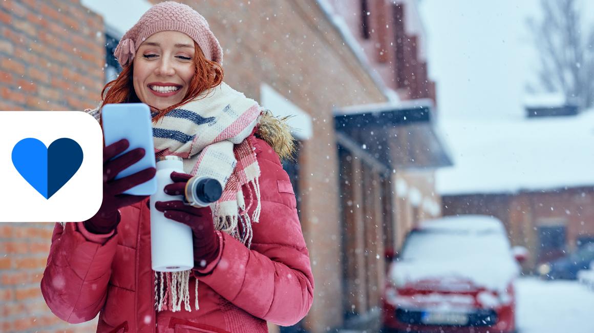 dziewczyna opatulona, w tle zima w mieście, ona z komorka