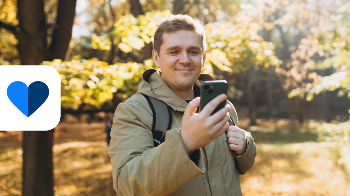Pan przy kości na spacerze z telefonem, w tle jesienny park