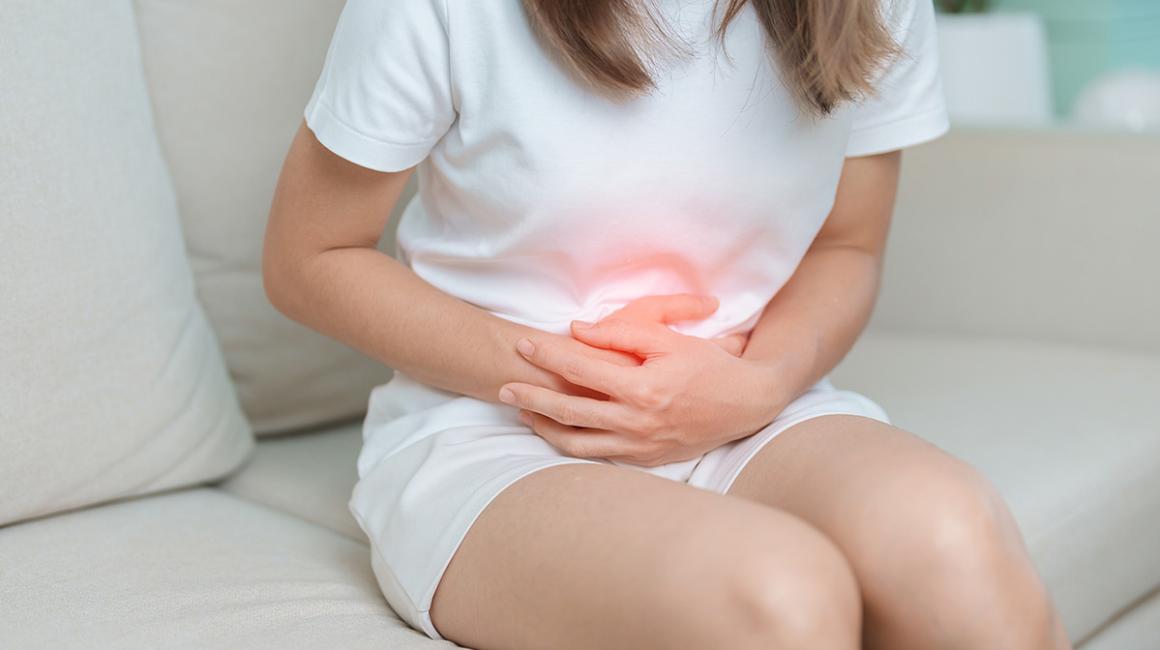 Dziewczyna siedzi i trzyma się za brzuch