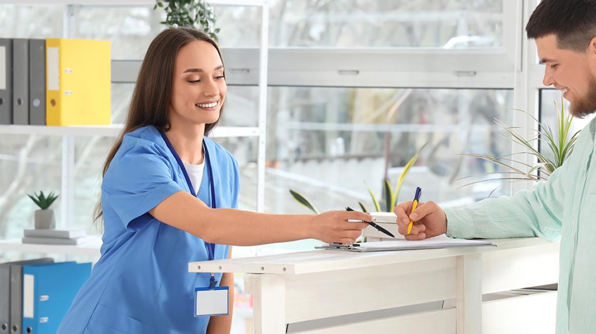 Rejestratorka pokazuje pacjentowi formularz