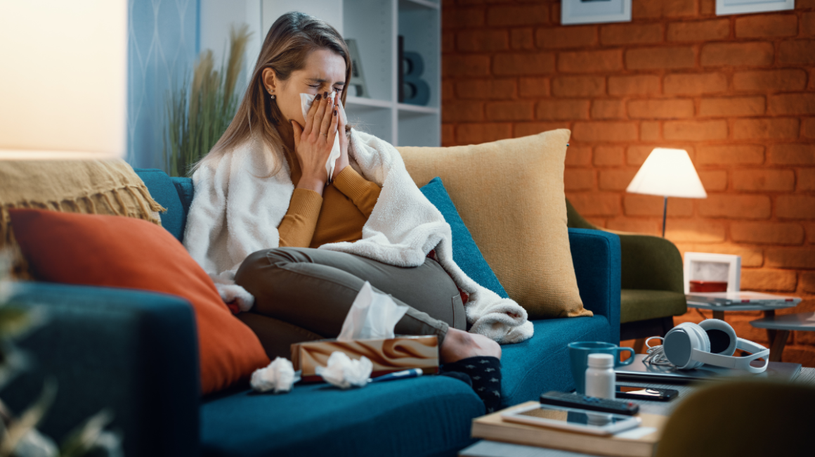 Kobieta siedzi na kanapie i wyciera nos
