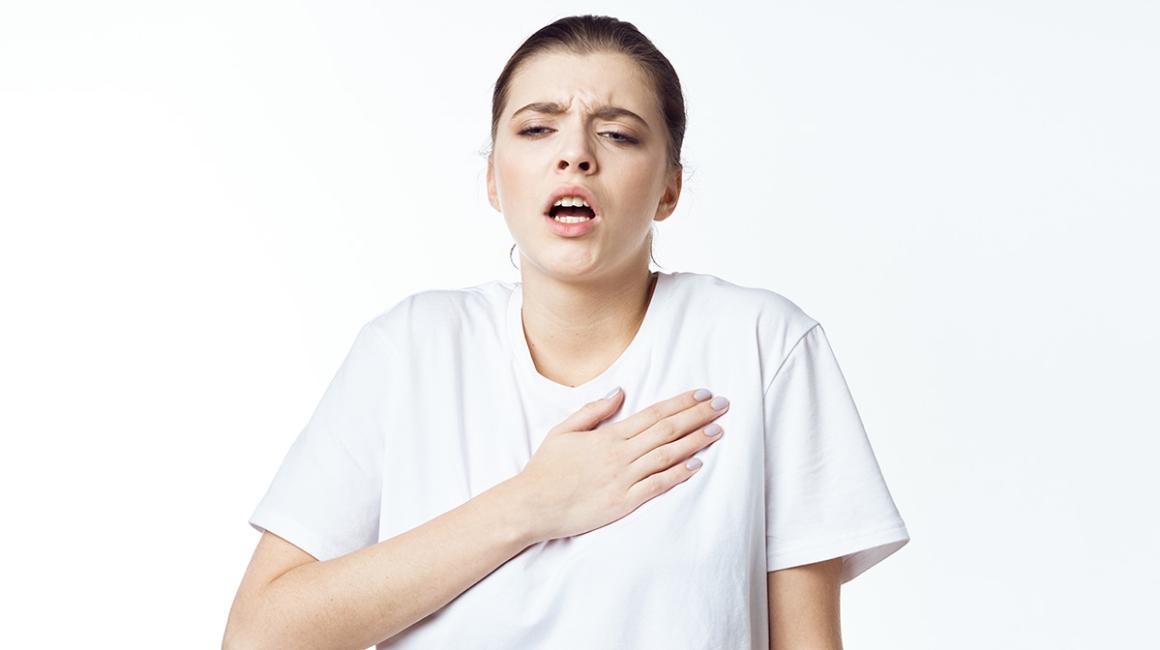 Mloda kobieta trzyma rękę na klatce piersiowej