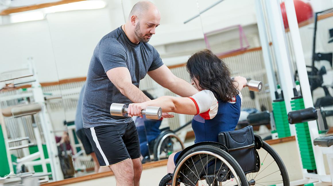 kobieta na wózku ćwiczy z fizjoterapeutą