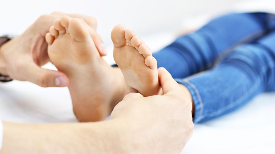 Lekarz bada dłońmi stopy dziecka