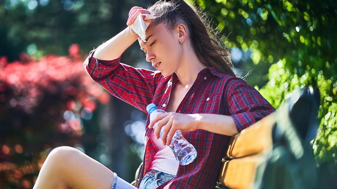 kobieta siedzi na ławce i ociera twarz chustką