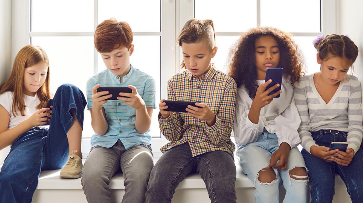 Grupa dzieci ze smartfonami na parapecie