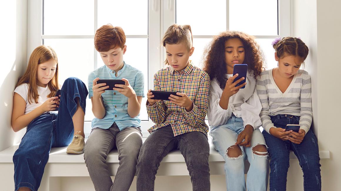 Grupa dzieci ze smartfonami na parapecie