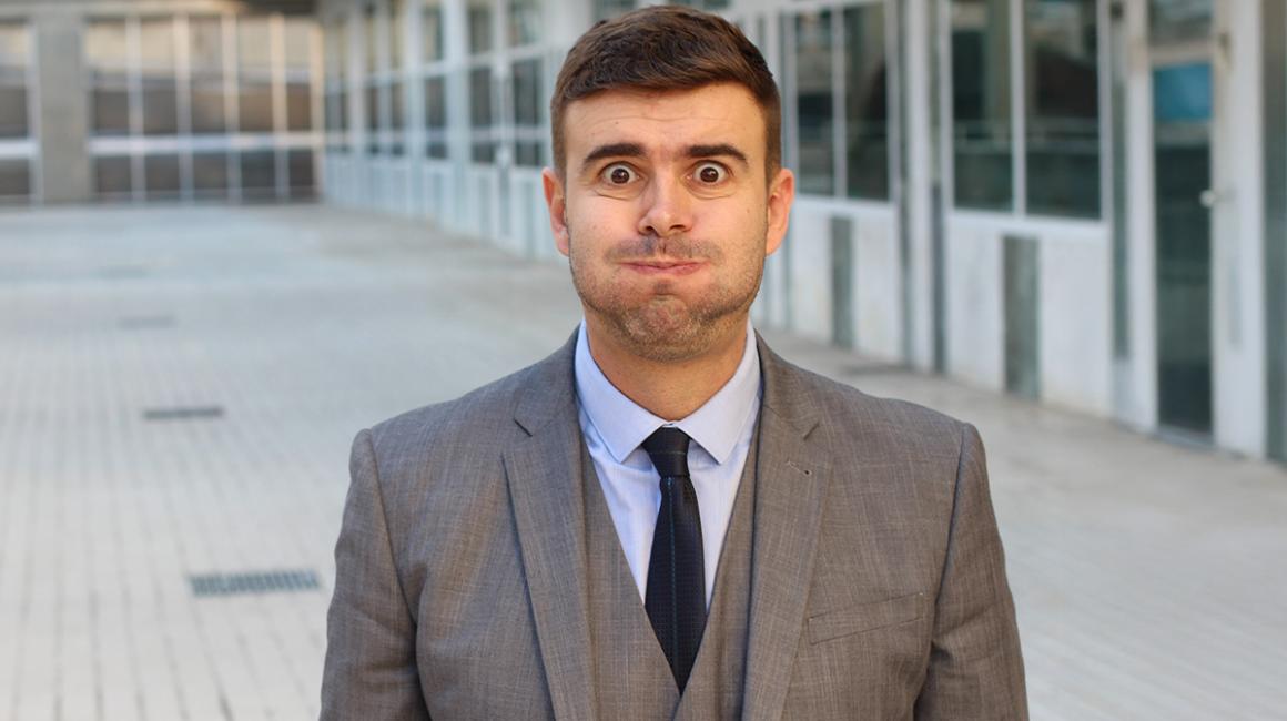 Mężczyzna w garniturze wydyma policzki.