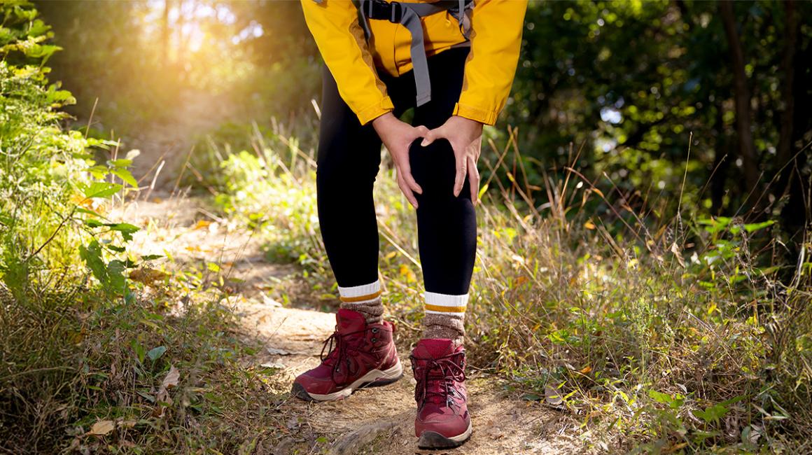 mężczyzna ubrany na sportowo chwyta się za kolano