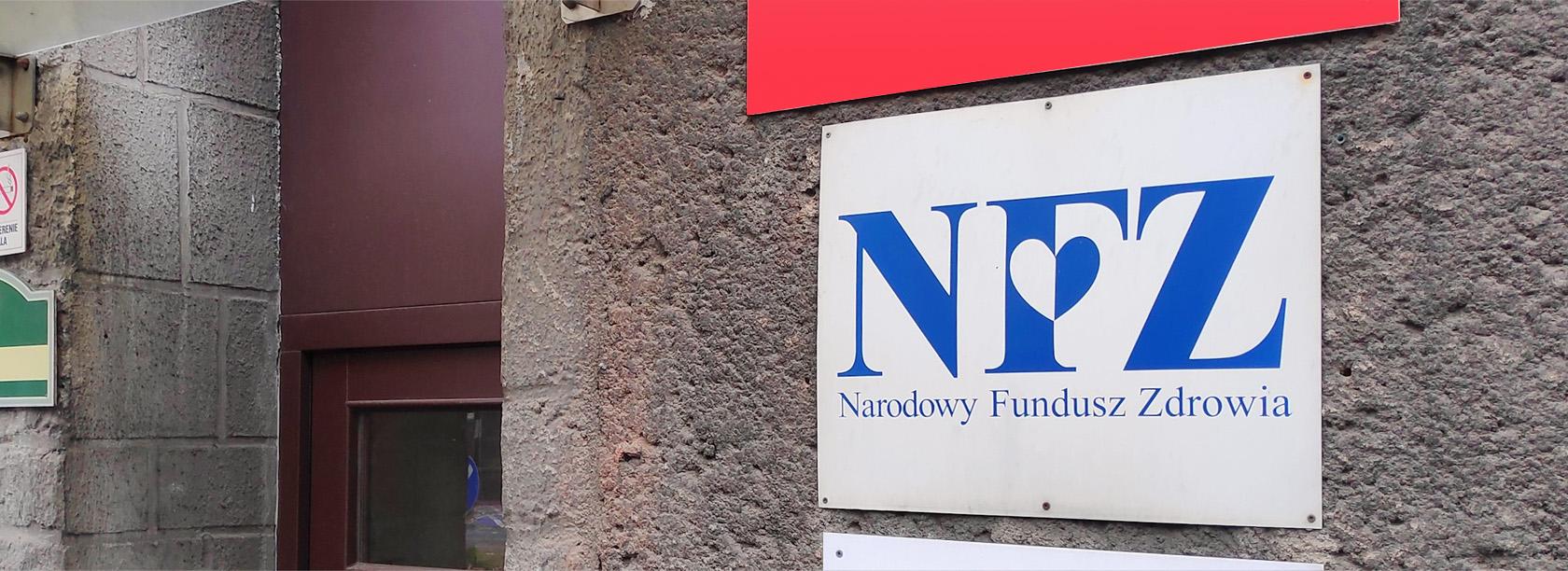 Tabliczka z logo NFZ na ścianie budynku.