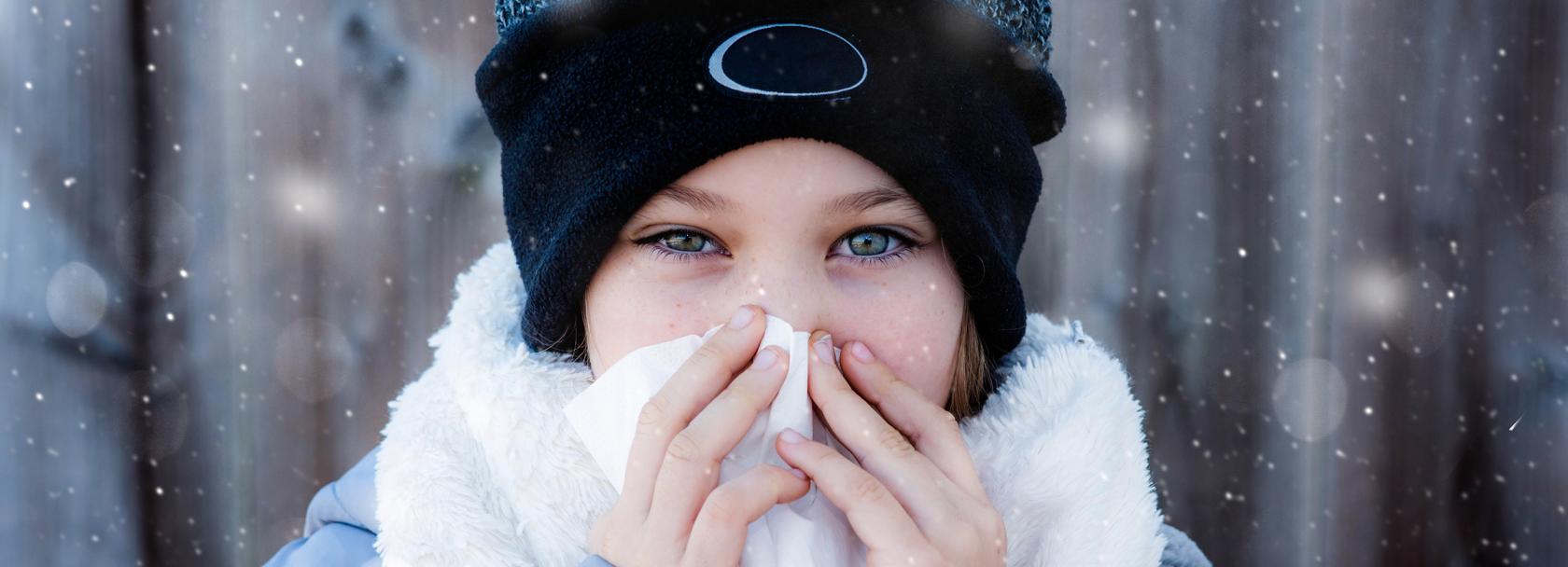 Ciepło ubrana kobieta z chusteczką przy nosie