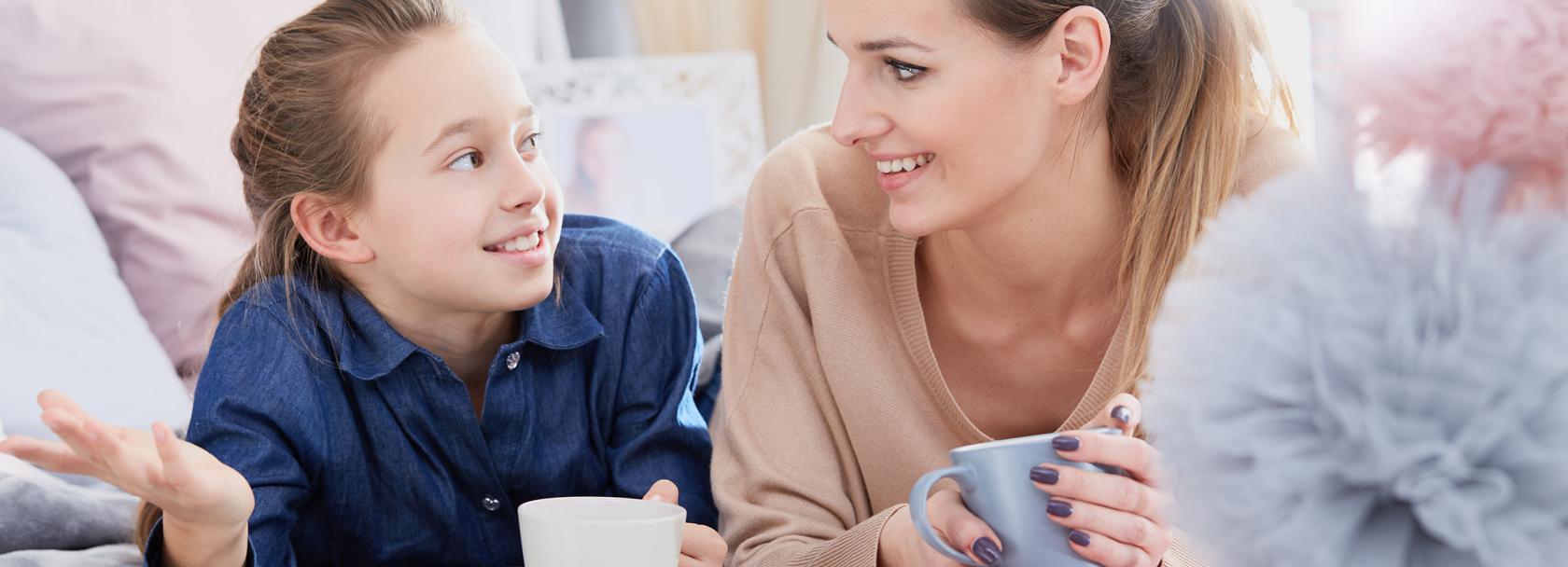 Mama i córka leżą na łóżku z herbatą i rozmawiają