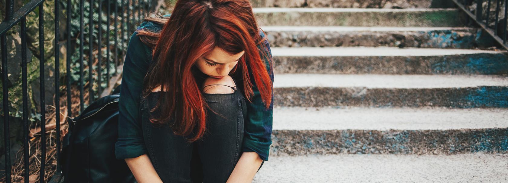 Smutna dziewczynka siedzi na kamiennych schodach