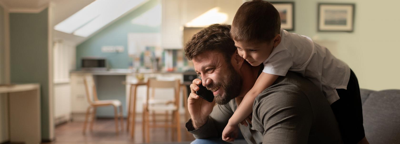 Syn wchodzi na plecy ojcu, który rozmawia przez telefon