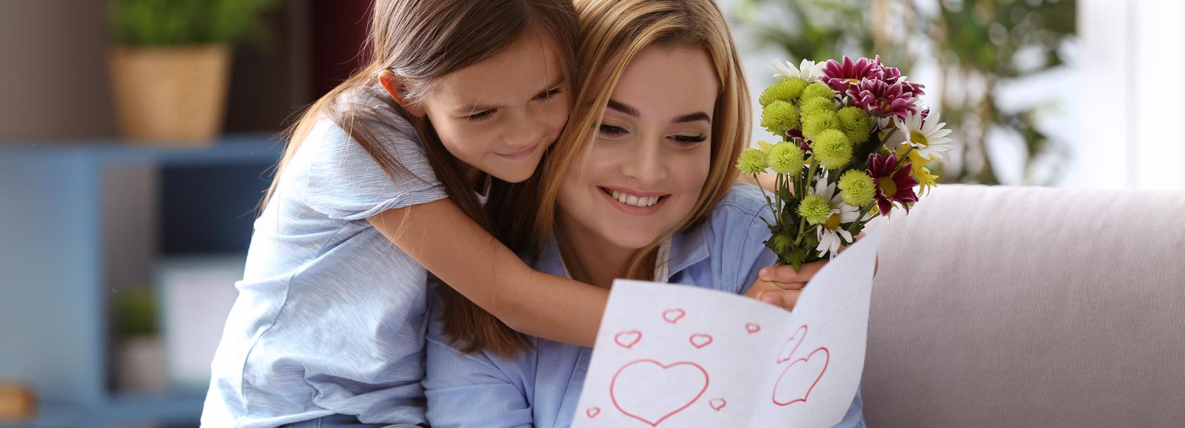 Dziewczynka przytula się do matki, która ogląda laurkę