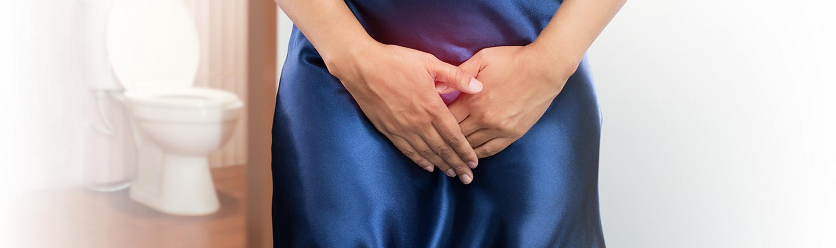 Wykadrowana kobieta z rękoma na układzie moczowym. Z lewej striny w tle toaleta.