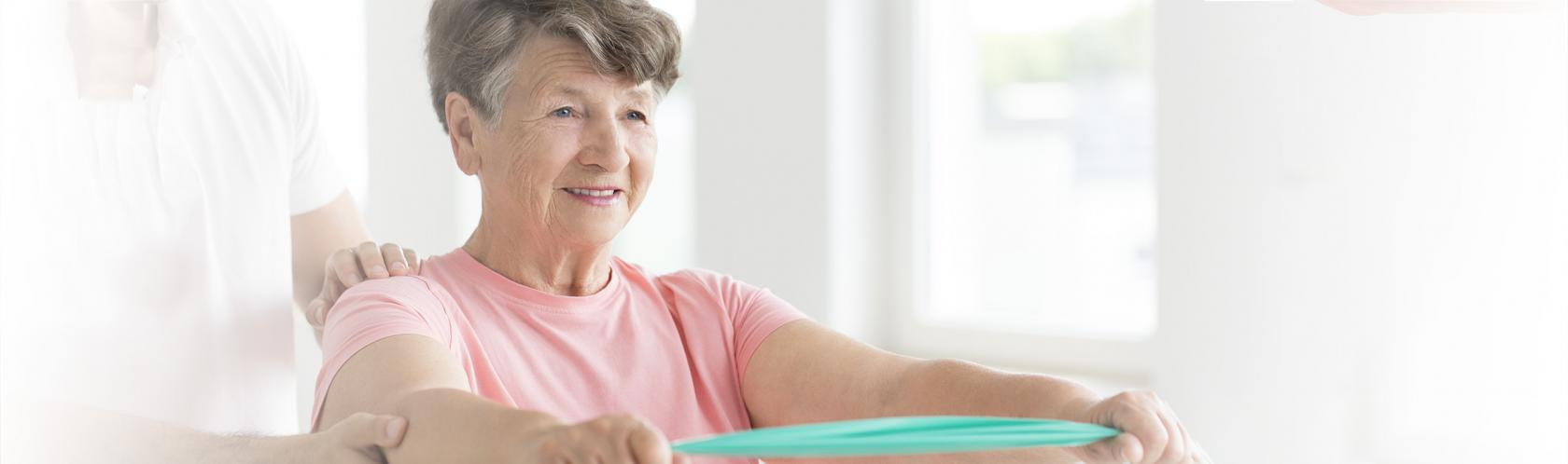 Starsza pani ćwiczy pod okiem fizjoteraputy 