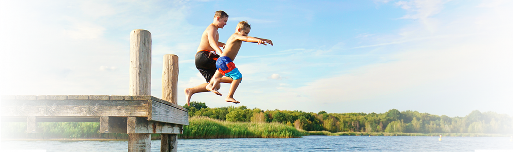 Dzieci skaczące z pomostu do jeziora